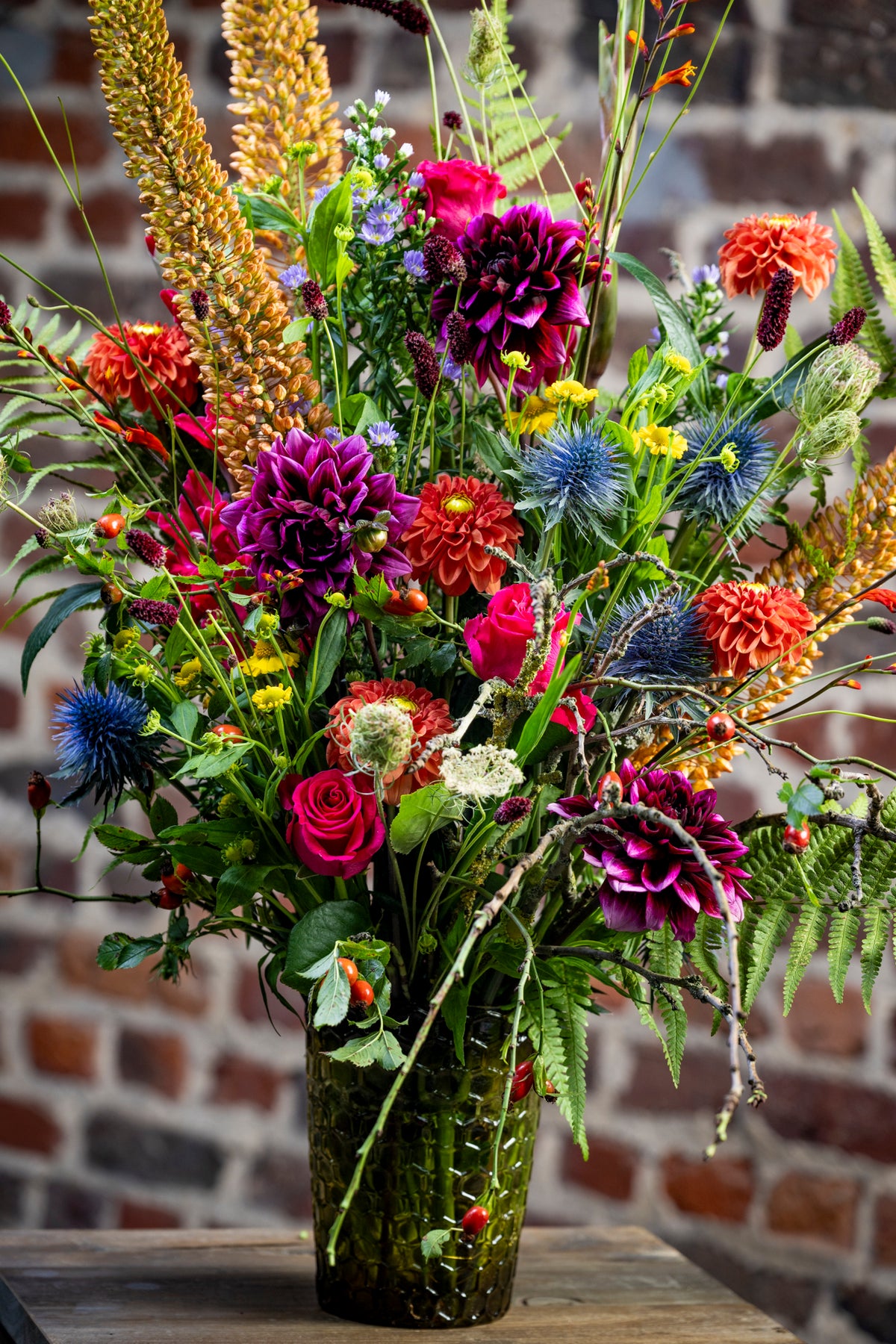 Groot zomerboeket met dahlia's, blauwe distels en hoge gele aren in een groene glazen vaas, workshop Late Summer Bouquet